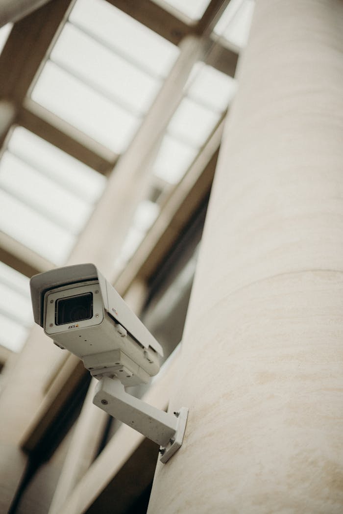services-02 Close-up of a security camera on a building wall, showcasing surveillance technology.