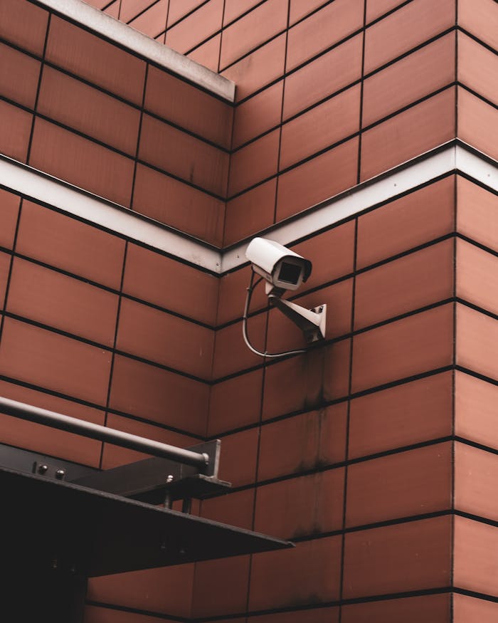 services-04 Security camera monitoring a red brick building exterior, symbolizing modern surveillance in Germany.